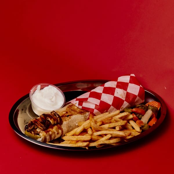 Shawarma wrap with fries, pickled vegetables, and a side of white sauce on a metal plate.