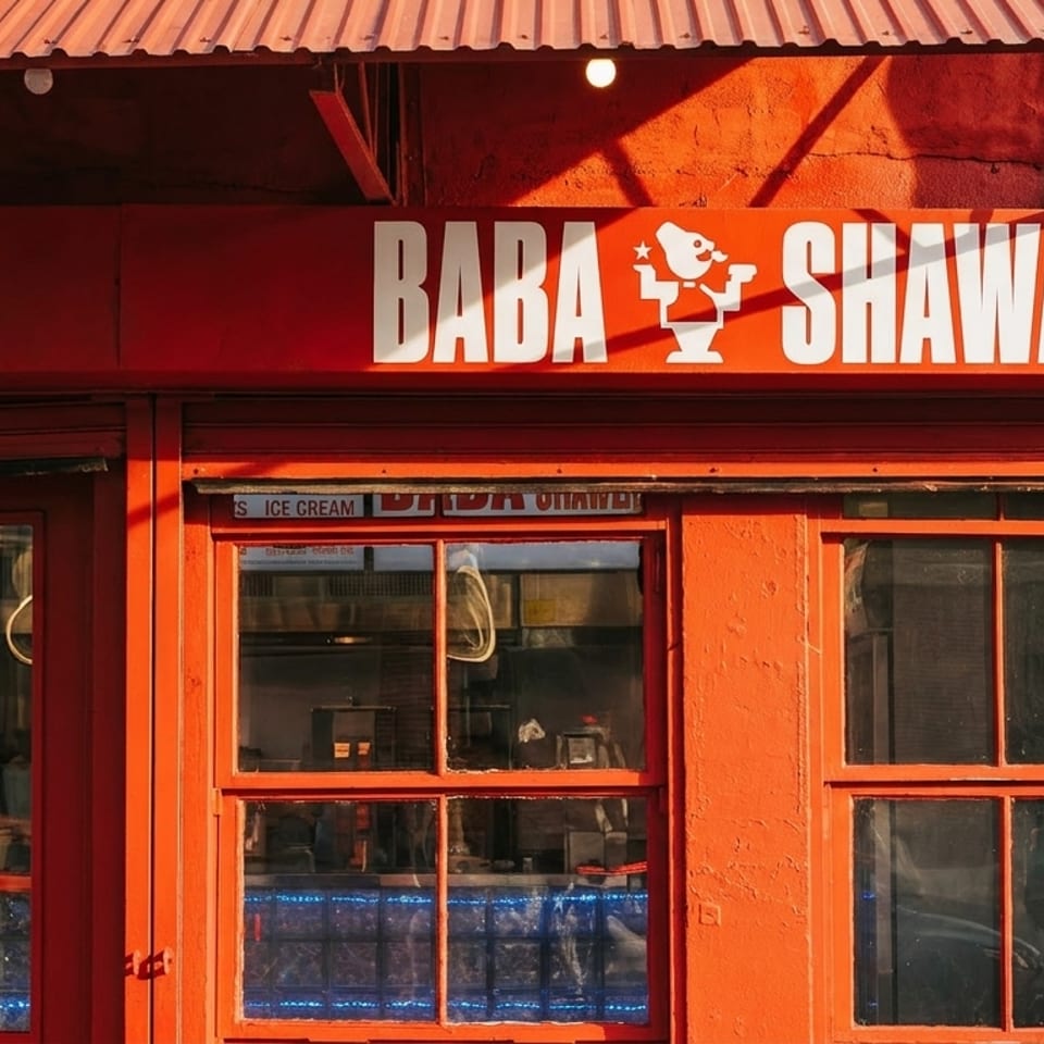 Bright red storefront of Baba Shawarma restaurant with white lettering and a cartoon logo.